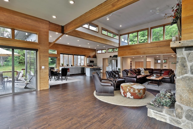 living room featuring wood walls, a towering ceiling, and beam ceiling