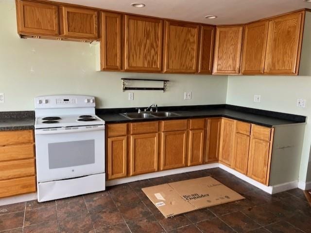 kitchen featuring dark countertops, brown cabinets, a sink, and electric range