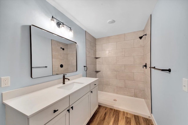 full bathroom featuring vanity, wood finished floors, and tiled shower