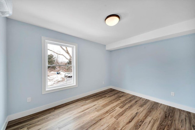 spare room with baseboards and wood finished floors