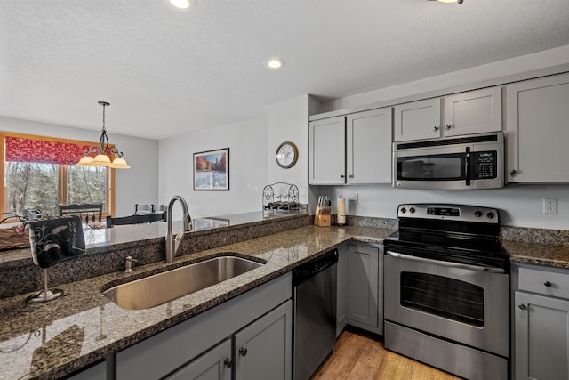 kitchen featuring dark stone counters, gray cabinets, sink, and stainless steel appliances