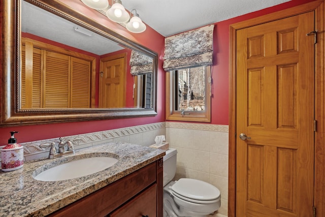 bathroom featuring vanity, toilet, and tile walls