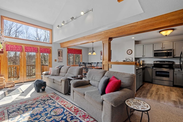 living room with dark hardwood / wood-style flooring, lofted ceiling, and an inviting chandelier