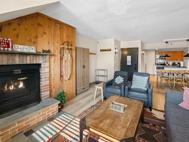 living room featuring a textured ceiling, a brick fireplace, and light hardwood / wood-style floors