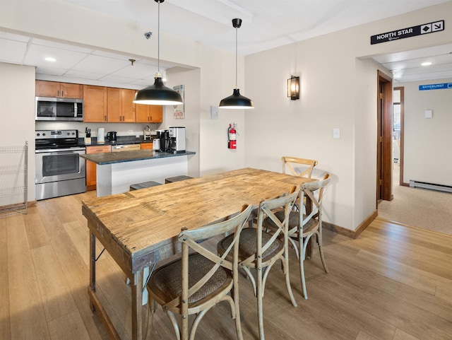 kitchen featuring decorative light fixtures, kitchen peninsula, sink, light wood-type flooring, and stainless steel appliances