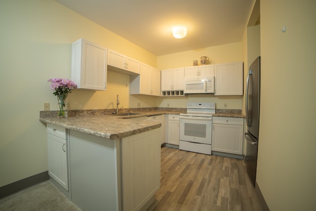 kitchen featuring white appliances, white cabinetry, sink, dark hardwood / wood-style floors, and kitchen peninsula