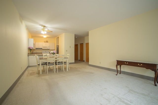 dining area with ceiling fan and light colored carpet