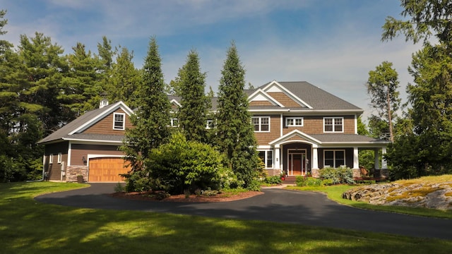 craftsman-style home featuring a front yard, covered porch, and a garage