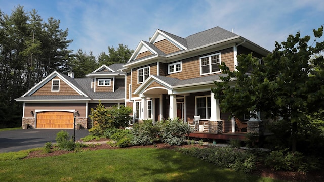 craftsman-style house with a front lawn, a garage, and covered porch