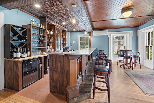 bar with wine cooler, crown molding, light hardwood / wood-style floors, and an AC wall unit