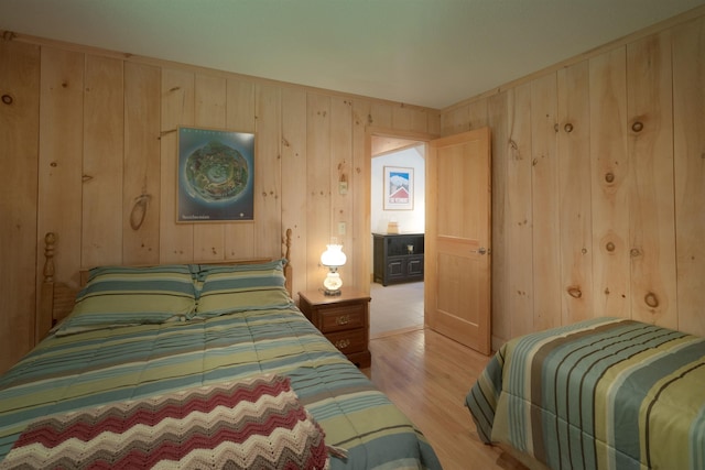 bedroom with wood walls and light wood-type flooring