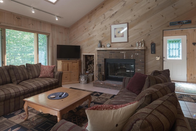 tiled living room featuring rail lighting, plenty of natural light, and wooden walls