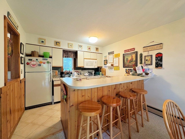 34 Sugar Brook Rd Unit F4, Peru, VT 05152 - kitchen featuring white appliances, a peninsula, light countertops, and a breakfast bar area