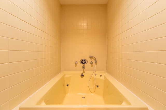 bathroom featuring a bath and tile walls