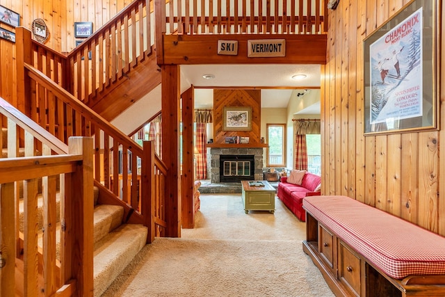 carpeted living room featuring wooden walls and a fireplace