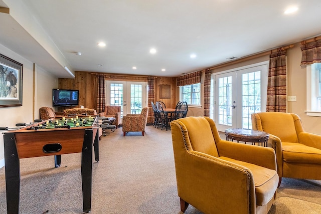 recreation room featuring wood walls, french doors, and light colored carpet