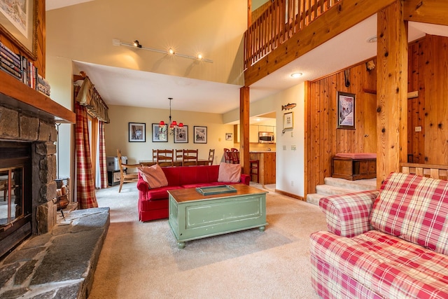 carpeted living room with high vaulted ceiling, wooden walls, and a stone fireplace