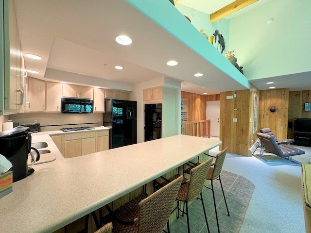 kitchen featuring wooden walls, kitchen peninsula, and black appliances