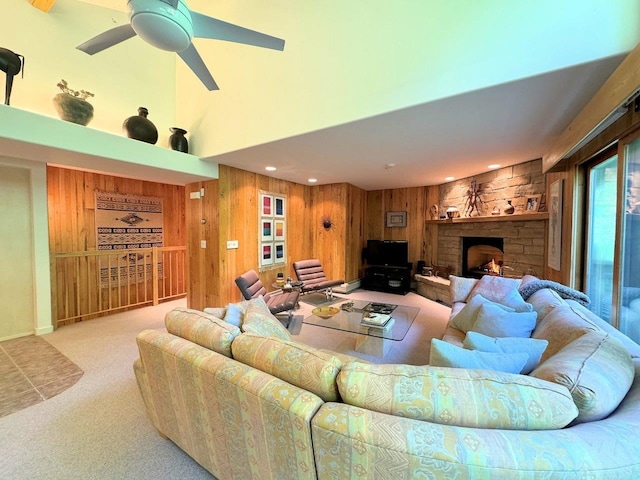 carpeted living room featuring a stone fireplace, wooden walls, and ceiling fan