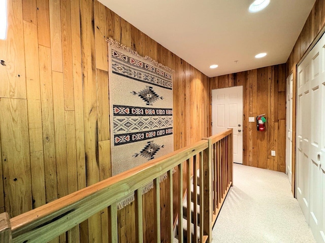 hallway featuring light carpet and wood walls