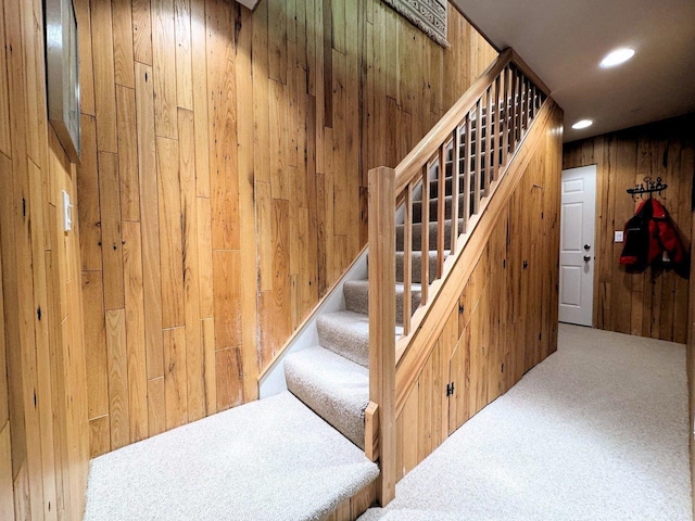 stairway with carpet floors and wooden walls