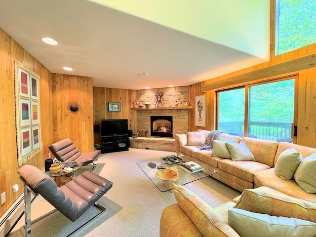 living room with a baseboard radiator, wooden walls, a stone fireplace, and carpet