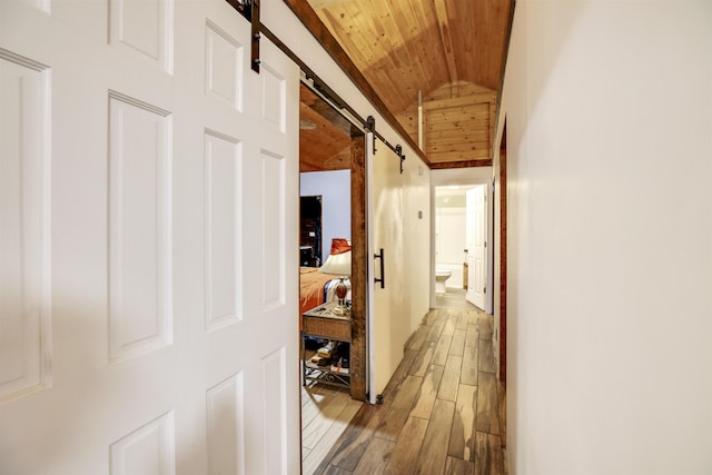 hallway featuring wood ceiling, a barn door, vaulted ceiling, and light wood-type flooring