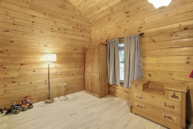 additional living space with wooden walls, high vaulted ceiling, and light wood-type flooring