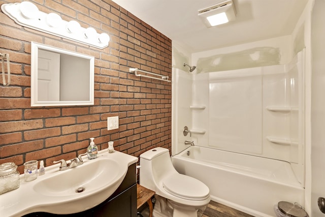 full bathroom with shower / bath combination, vanity, brick wall, and toilet