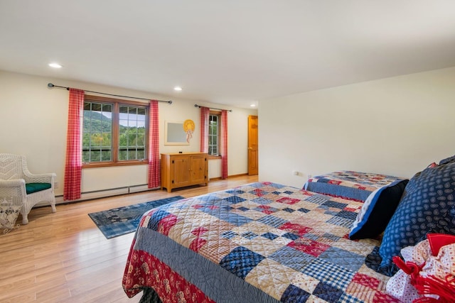 bedroom with light hardwood / wood-style flooring and baseboard heating