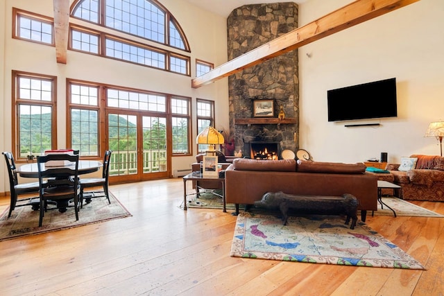 living room featuring a fireplace, a high ceiling, light hardwood / wood-style flooring, and baseboard heating