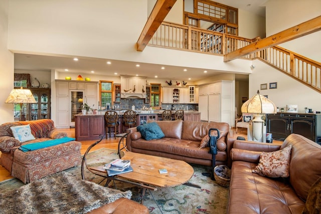 living room featuring beamed ceiling, light hardwood / wood-style floors, and a towering ceiling