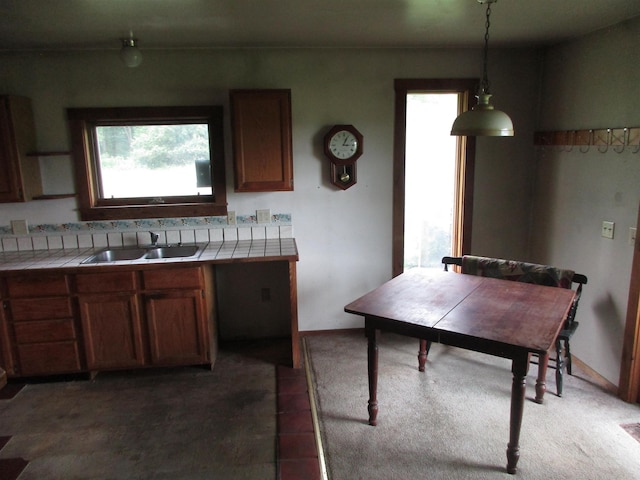 kitchen featuring a sink, hanging light fixtures, tile countertops, and a wealth of natural light