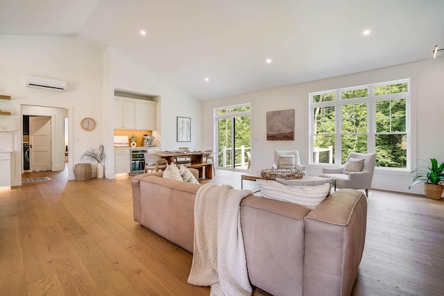 living room with lofted ceiling, a wall mounted air conditioner, a healthy amount of sunlight, beverage cooler, and light wood-type flooring