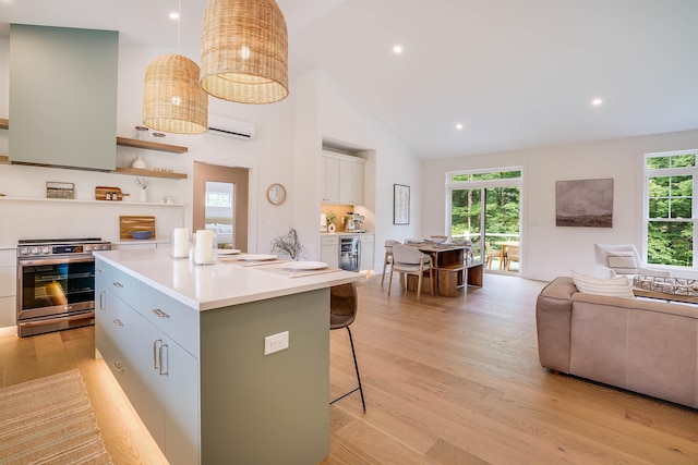 kitchen with a center island with sink, electric range, a kitchen bar, and light hardwood / wood-style flooring