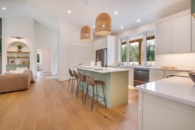 kitchen featuring white cabinetry, decorative light fixtures, built in features, a kitchen island, and stainless steel appliances