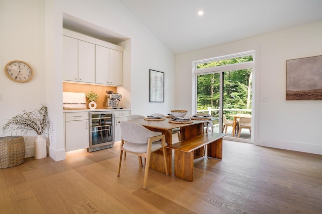 dining area featuring lofted ceiling, wine cooler, and light hardwood / wood-style flooring