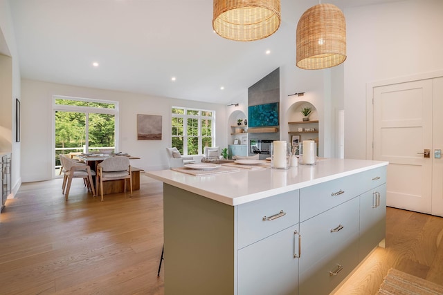 kitchen with a fireplace, built in shelves, light wood-type flooring, and a kitchen island