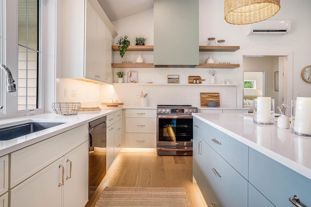 kitchen featuring sink, stainless steel range with electric cooktop, a wall mounted AC, light hardwood / wood-style flooring, and a healthy amount of sunlight