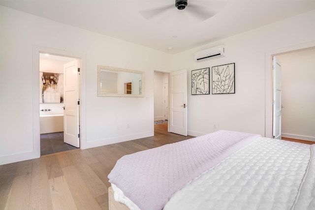 bedroom featuring hardwood / wood-style flooring, a wall mounted air conditioner, connected bathroom, and ceiling fan