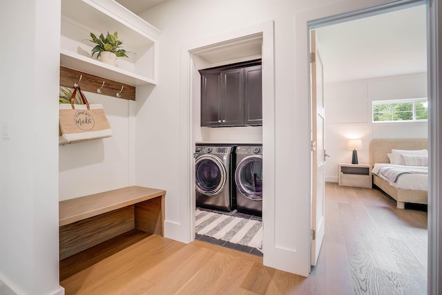 washroom with cabinets, light hardwood / wood-style floors, and washer and dryer