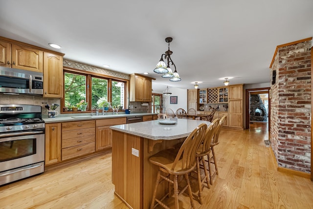 kitchen featuring light countertops, appliances with stainless steel finishes, a breakfast bar, and light wood-style floors