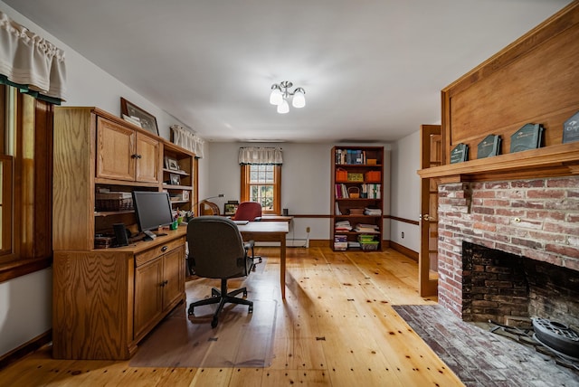 office space with a brick fireplace, light wood-style flooring, and baseboards