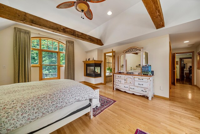 bedroom with baseboards, lofted ceiling with beams, light wood-style flooring, a multi sided fireplace, and recessed lighting