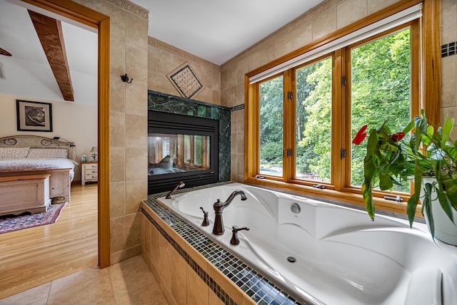 full bathroom featuring a bath, tile patterned flooring, and tile walls