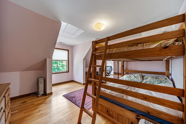 bedroom featuring light wood-style floors, baseboards, and vaulted ceiling