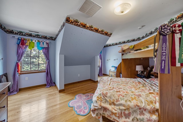 bedroom with baseboards, visible vents, vaulted ceiling, and wood finished floors