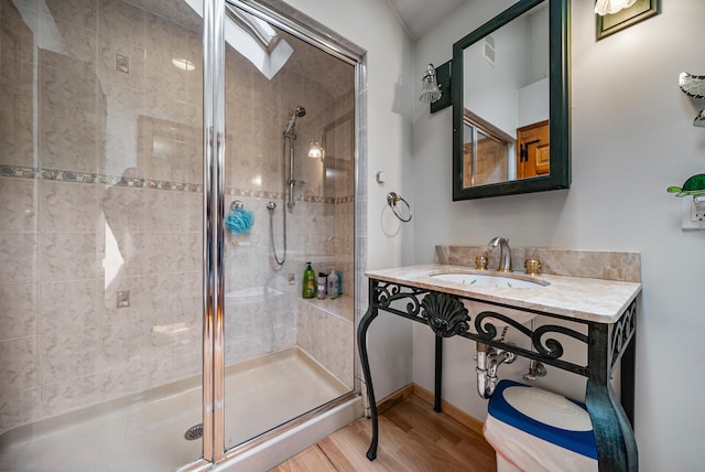 full bathroom featuring a stall shower, visible vents, a sink, and wood finished floors