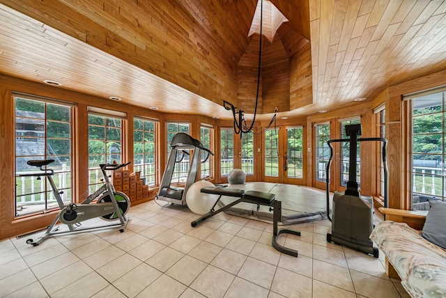 exercise room featuring a skylight, wood ceiling, high vaulted ceiling, and light tile patterned flooring