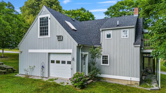 view of front of home with a detached garage, a chimney, a shingled roof, board and batten siding, and a front yard